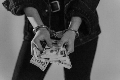 person with handcuffs and money